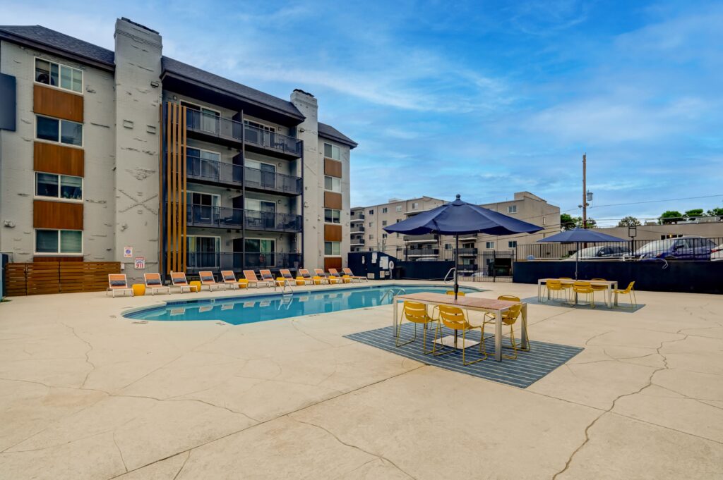 Apartment pool with lounge chairs, and building in the background.