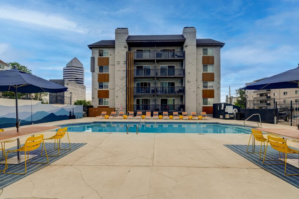Apartment pool with lounge chairs, mural backdrop, and building in the background.