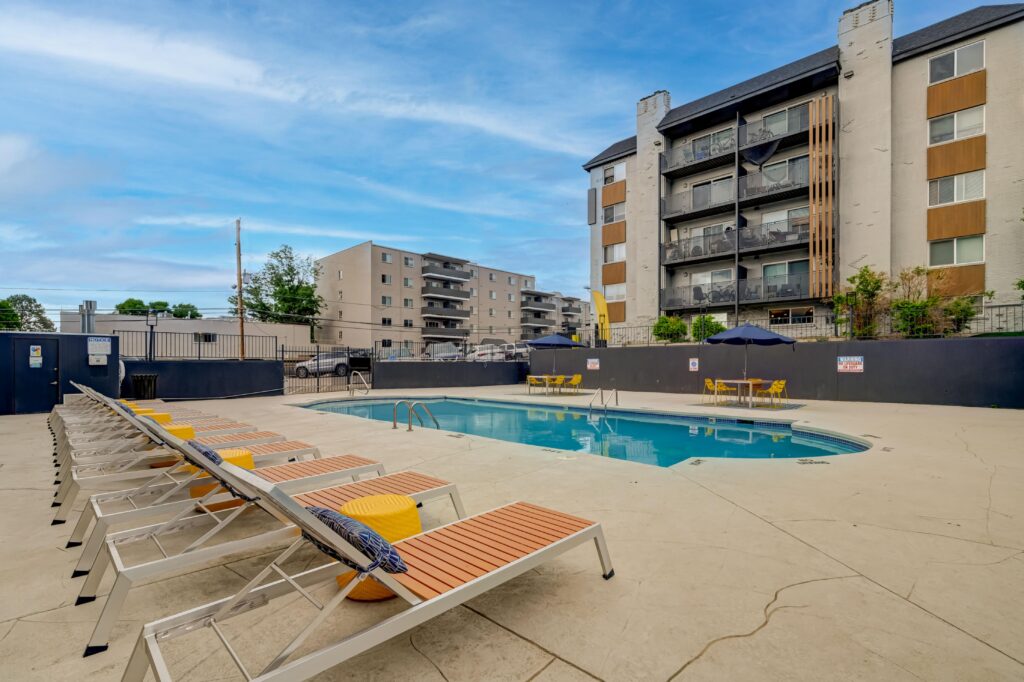 Apartment pool with lounge chairs, mural backdrop, and building in the background.